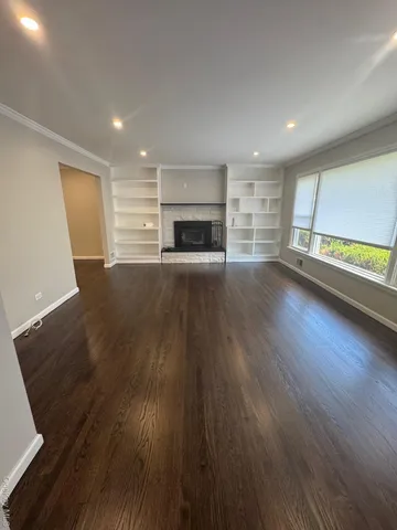 an empty room with wooden floor fireplace and windows