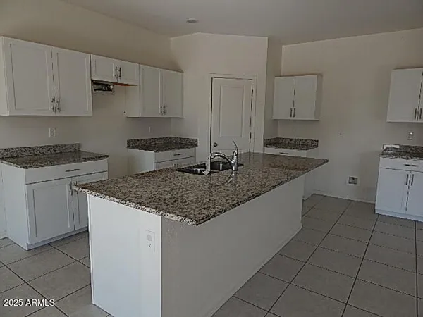 a kitchen with granite countertop a sink a stove and cabinets