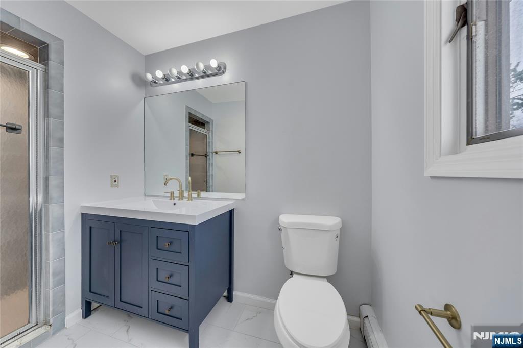 2410 3rd Street Fort Lee, NJ 07024 - Photo 18 of 37 a bathroom with a toilet a sink a mirror a vanity and window