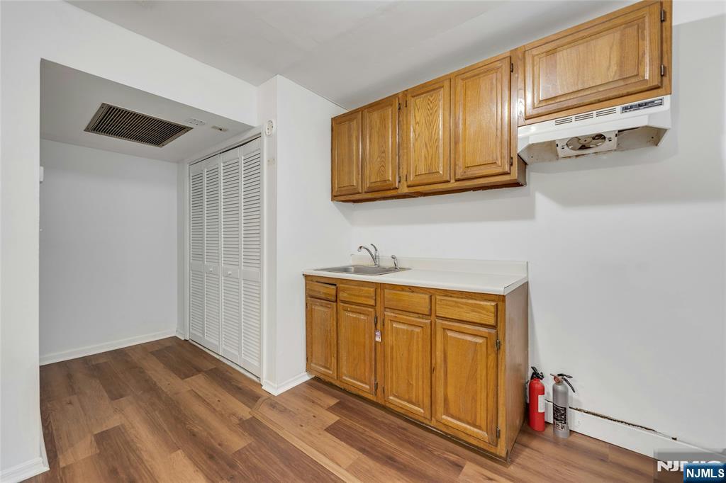 2410 3rd Street Fort Lee, NJ 07024 - Photo 24 of 37 a hallway with stainless steel appliances granite countertop a sink dishwasher stove and wooden cabinets