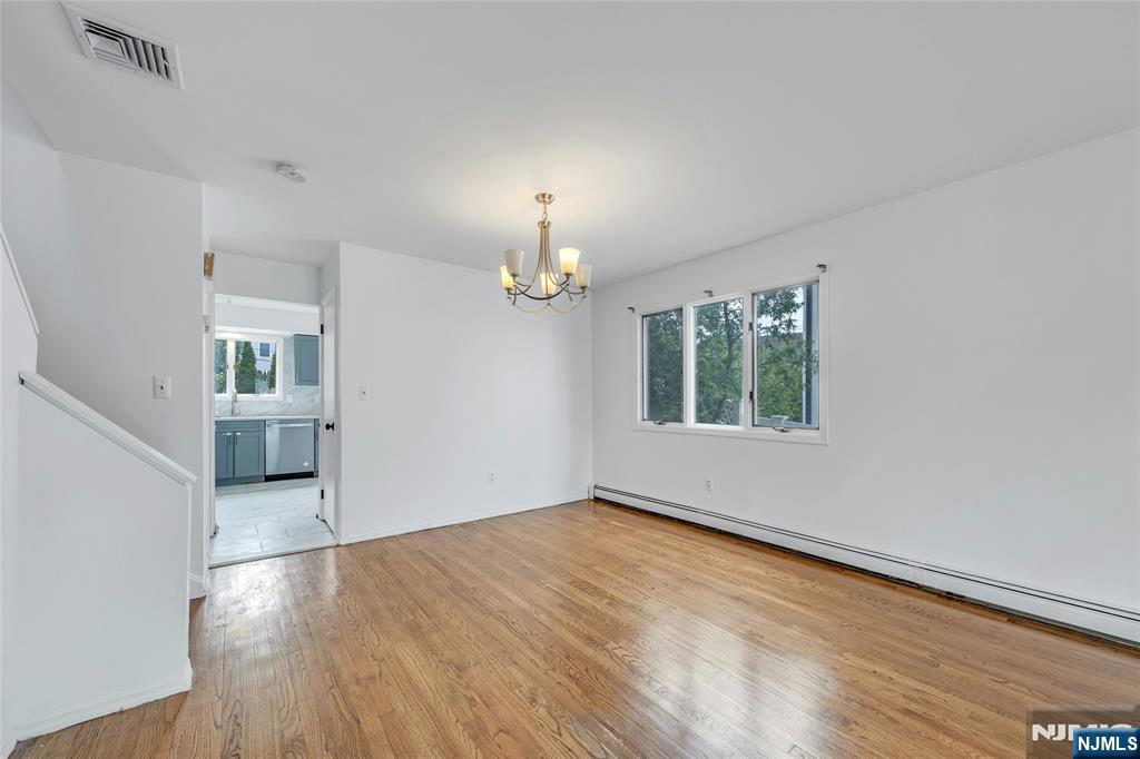 2410 3rd Street Fort Lee, NJ 07024 - Photo 6 of 37 an empty room with wooden floor chandelier and windows