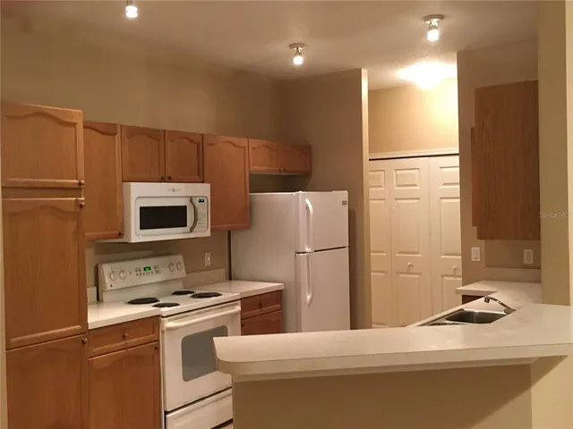 a kitchen with a sink a refrigerator and a stove top oven