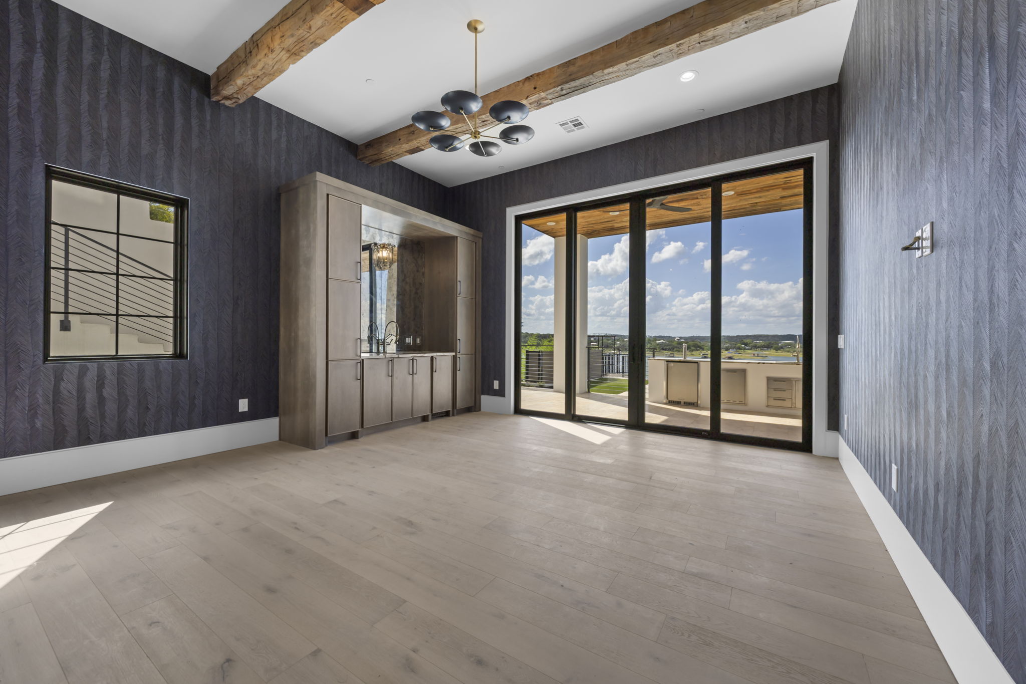 1496 Buffalo Gap Road Lakeway, TX 78734 - Photo 34 of 37 Exposed wood beams crown this spacious room, featuring light hardwood flooring and a sophisticated wet bar.