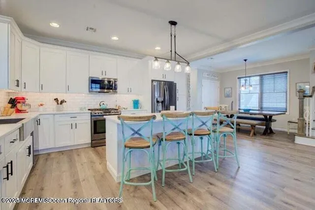 a kitchen with stainless steel appliances kitchen island granite countertop a stove a sink a dining table and chairs with wooden floor