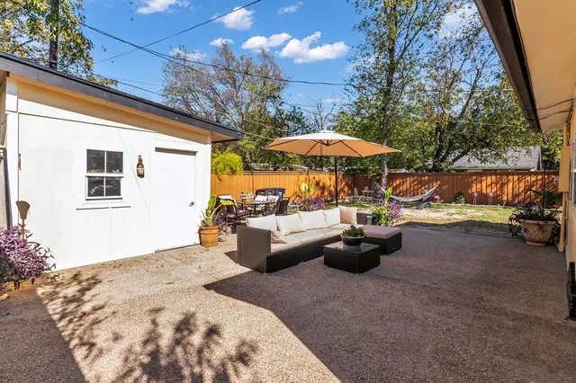 a view of a patio with couches table and chairs under an umbrella