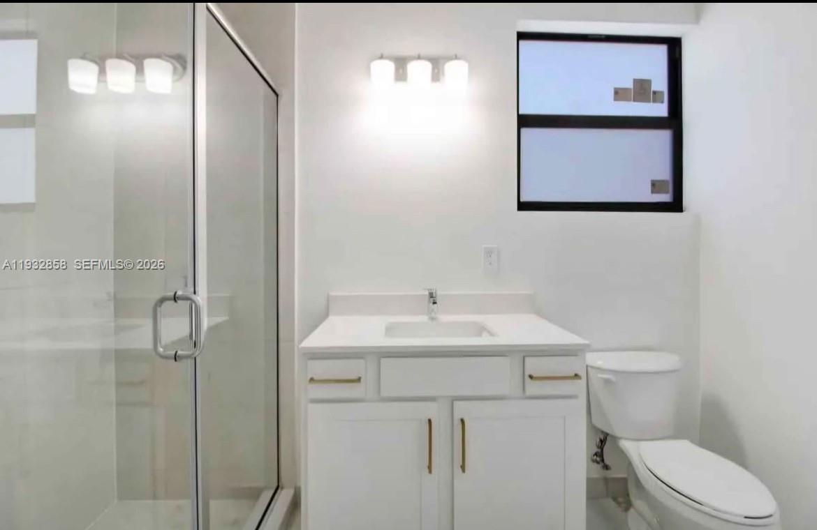 32207 Southwest 196th Avenue, Unit 2 Homestead, FL 33030 - Photo 4 of 8 a bathroom with a toilet sink vanity and mirror