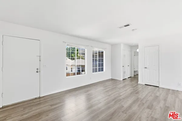 a view of an empty room with wooden floor and a window