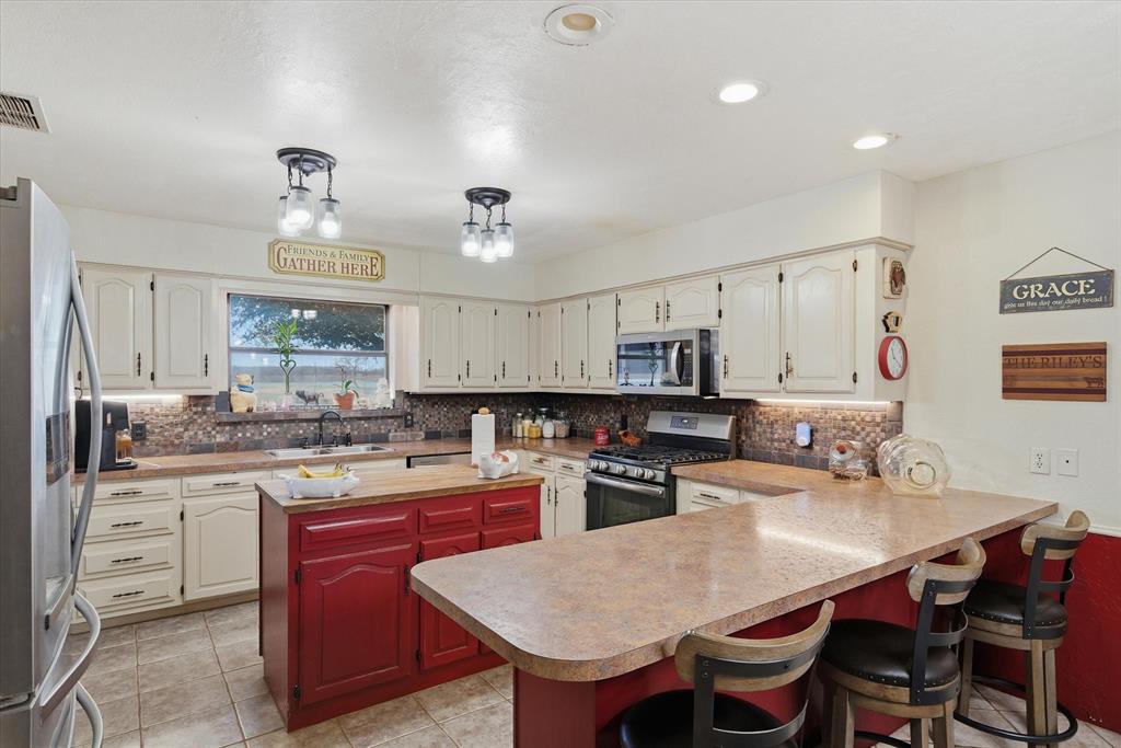 1700 Fm 1995 Van, TX 75790 - Photo 32 of 40 a kitchen with a stove a sink a kitchen island with chairs and wooden cabinets