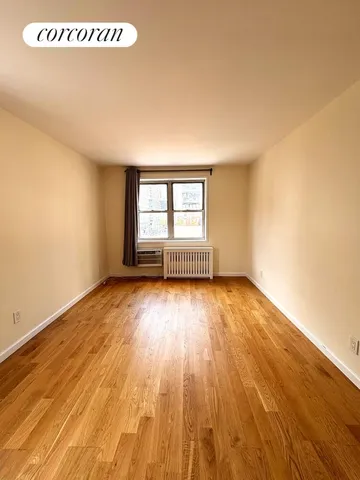 a view of empty room with window and wooden floor
