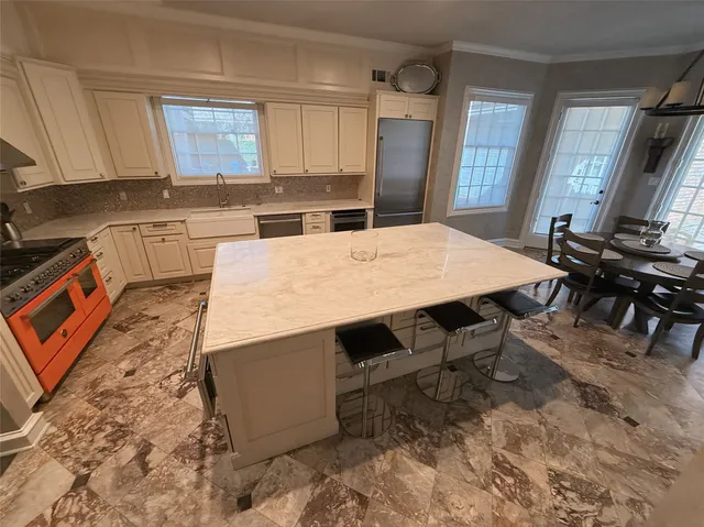 a kitchen with stainless steel appliances kitchen island granite countertop a refrigerator a stove a sink dishwasher and white cabinets with wooden floor