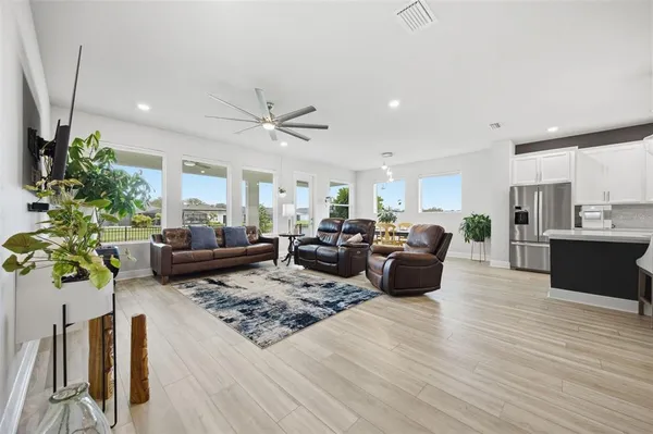 a kitchen with stainless steel appliances granite countertop a refrigerator a stove oven a sink dishwasher and white cabinets with wooden floor