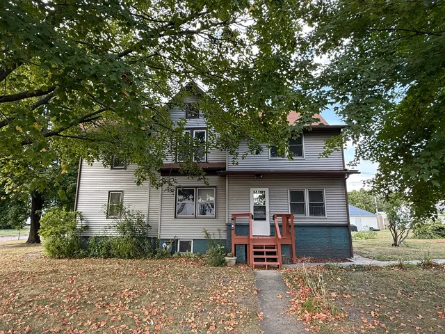 a front view of a house with a garden and tree