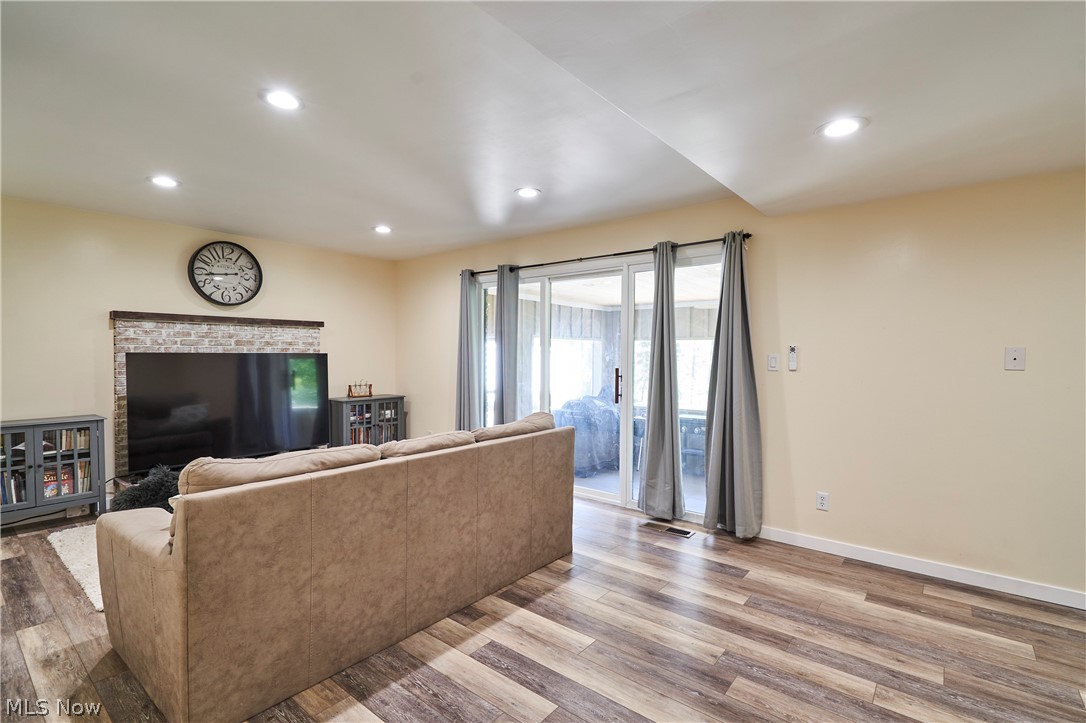 1535 Belle Meade Drive Akron, OH 44321 - Photo 18 of 33 Family room featuring a fireplace, recently installed LVT flooring, recessed canned lighting, updated paint, and a triple slider leading to a sunporch.