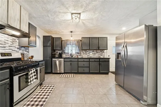 a kitchen with stainless steel appliances a refrigerator a stove a sink a counter top space and cabinets