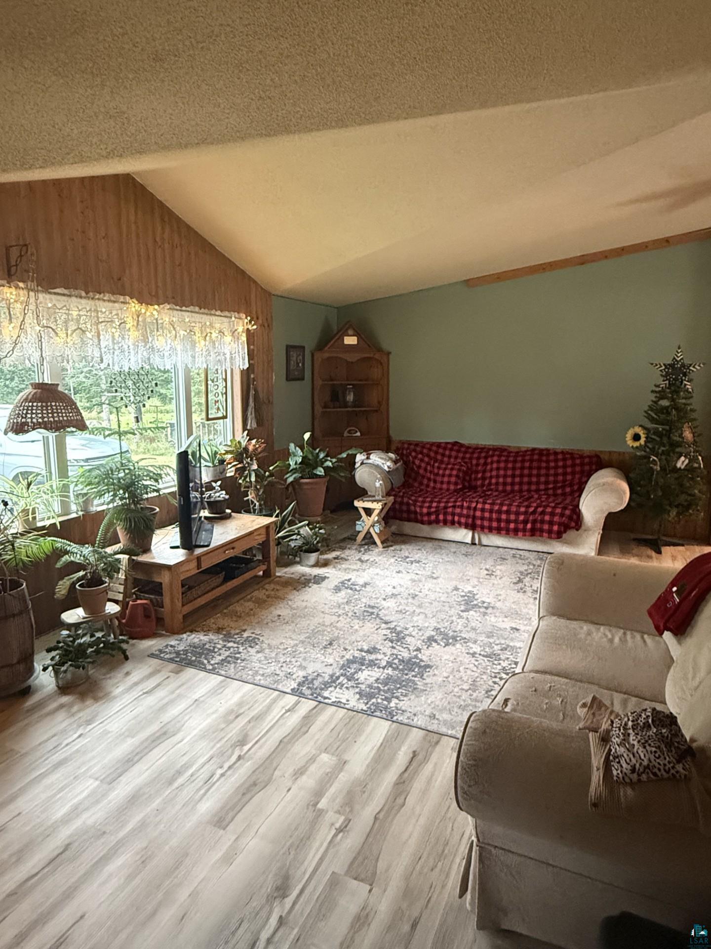 124 Nynas Road Esko, MN 55733 - Photo 3 of 14 Vaulted ceiling with exposed wood beam, wood-finish flooring, and a corner built-in shelving unit