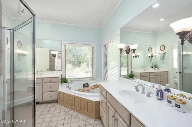 a bathroom with a tub sink double vanity mirror and next to a window