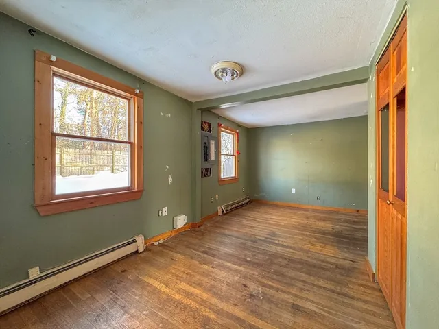a view of an empty room with wooden floor and a window