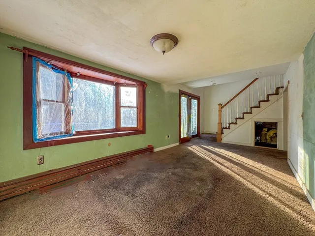 a view of an empty room with fireplace and a window