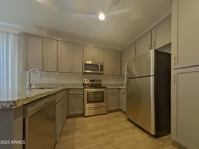 a kitchen with stainless steel appliances granite countertop a refrigerator and a sink