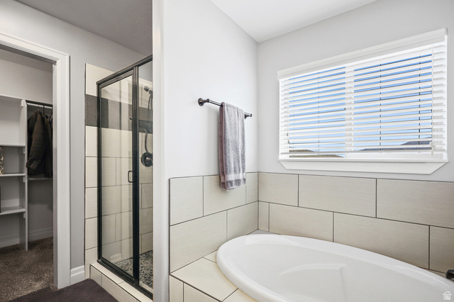 1588 West Rim Rock Drive Stockton, UT 84071 - Photo 21 of 61 Bathroom featuring a freestanding oval tub, a walk-in shower with black-framed glass enclosure, and white horizontal wall tiling
