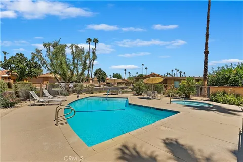 a view of a swimming pool with lawn chairs under an umbrella