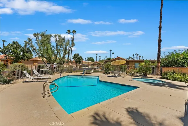a view of a swimming pool with lawn chairs under an umbrella