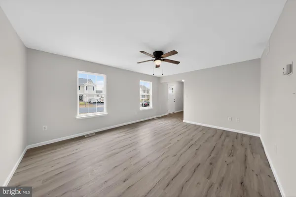 a view of an empty room with a window and wooden floor