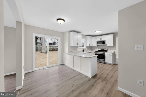 a kitchen with granite countertop a refrigerator and wooden floors