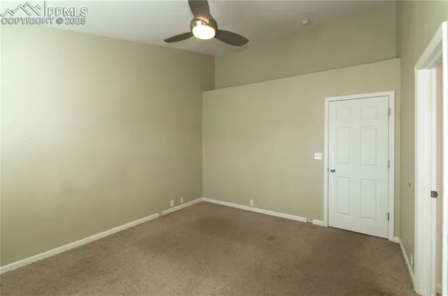 an empty room with a chandelier fan and closet
