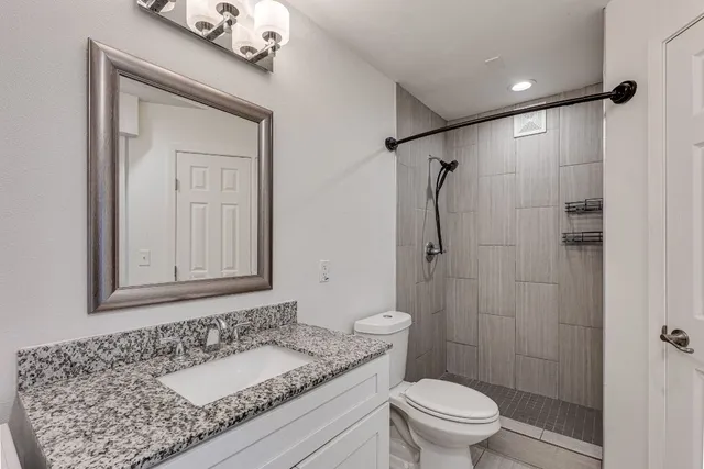 a bathroom with a granite countertop sink toilet and shower