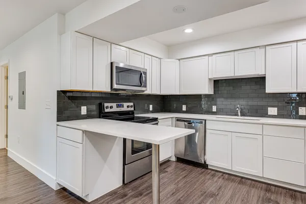 a kitchen with stainless steel appliances granite countertop a stove top oven a sink and white cabinets