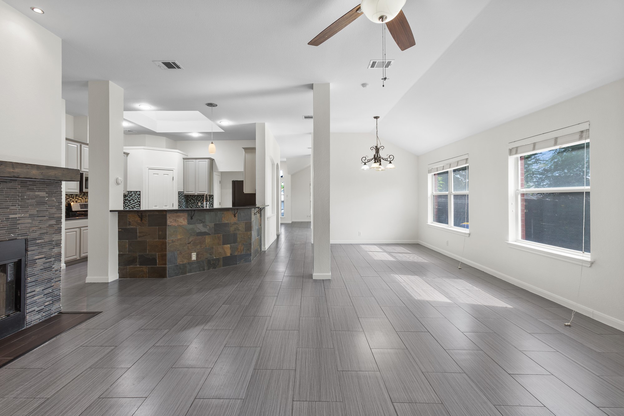 1201 Springbrook Road Pflugerville, TX 78660 - Photo 11 of 33 An open-concept living space features wood-look tile flooring and a stacked stone fireplace.