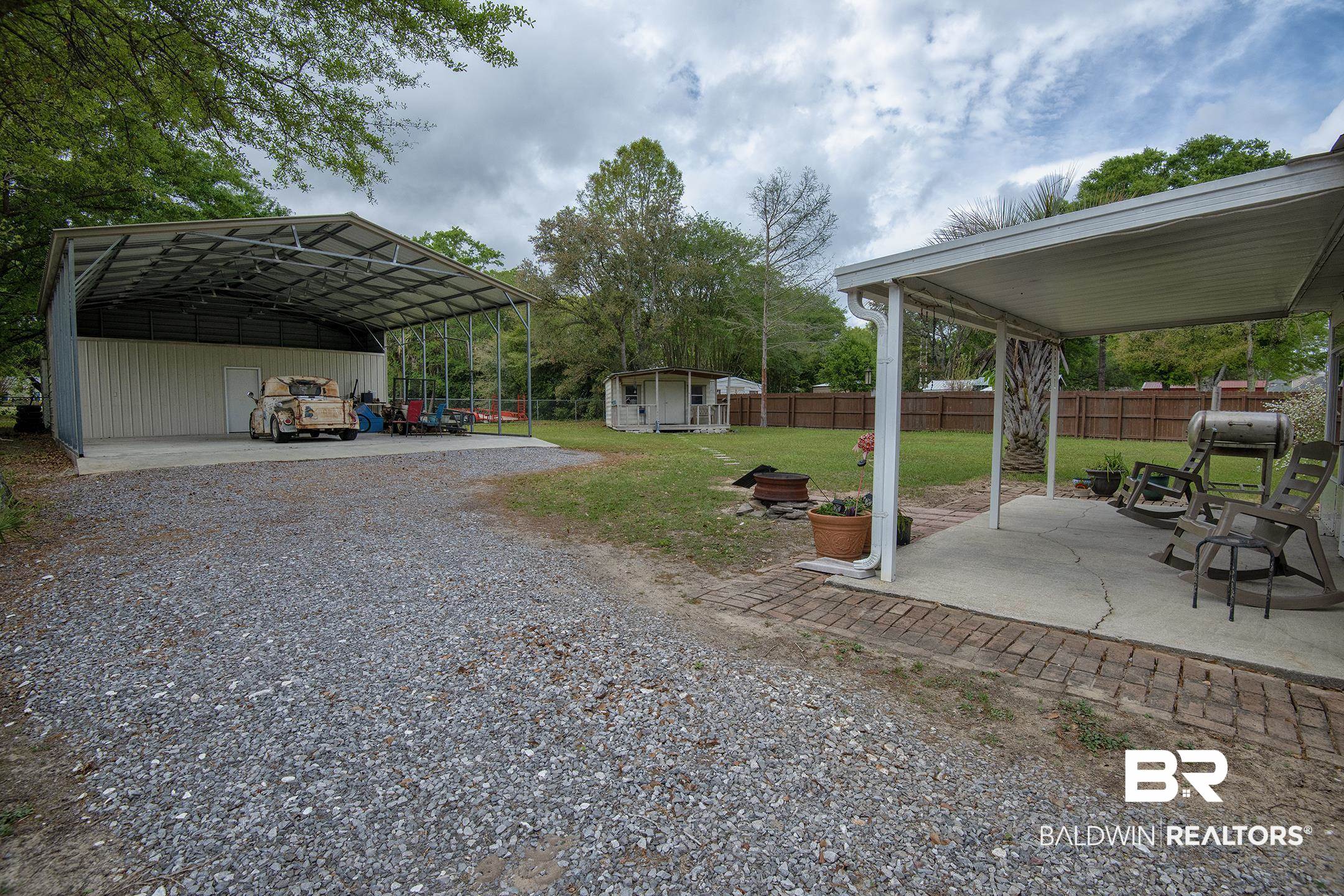 10093 Willis Road Foley, AL 36535 - Photo 26 of 33 Fenced backyard featuring a patio, a shed, a carport, and gravel driveway