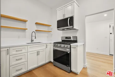a kitchen with stainless steel appliances white cabinets a stove top oven a sink and dishwasher