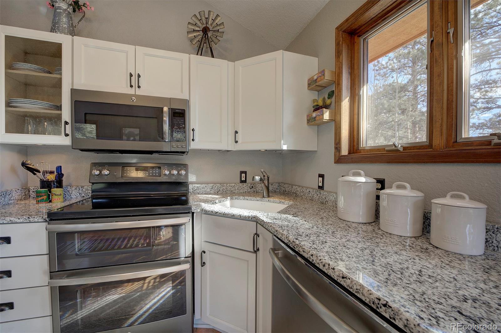 371 Hall Road Bailey, CO 80421 - Photo 8 of 40 a kitchen with granite countertop a stove a sink and a microwave