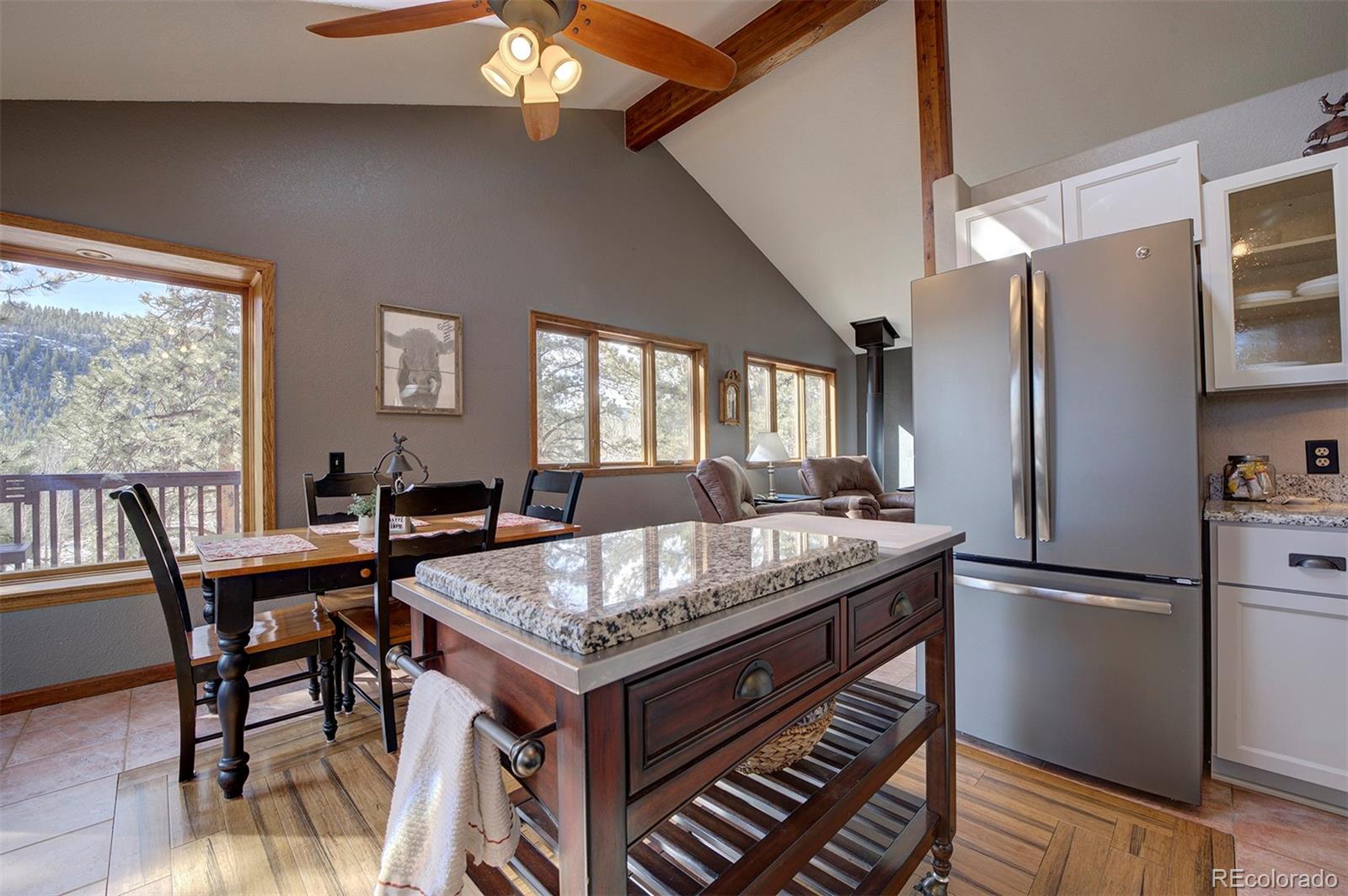 371 Hall Road Bailey, CO 80421 - Photo 10 of 40 a kitchen with granite countertop stainless steel appliances a table chairs and a refrigerator