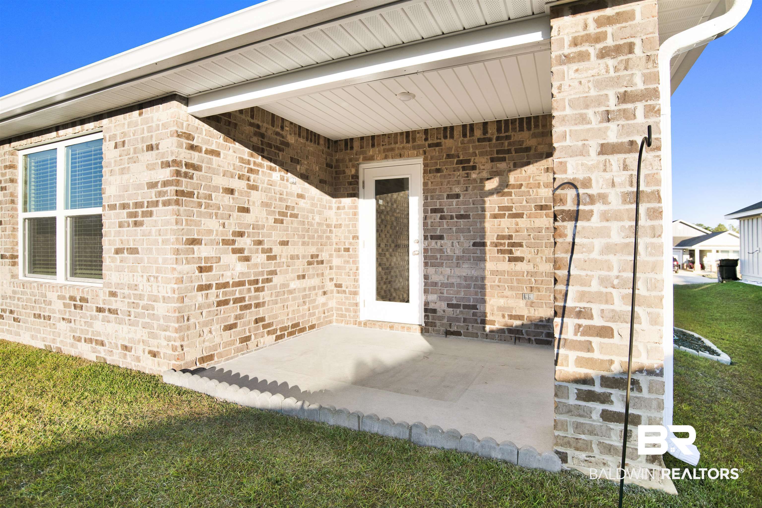 32038 Lyon Road Daphne, AL 36527 - Photo 29 of 30 View of exterior entry featuring brick siding and a lawn