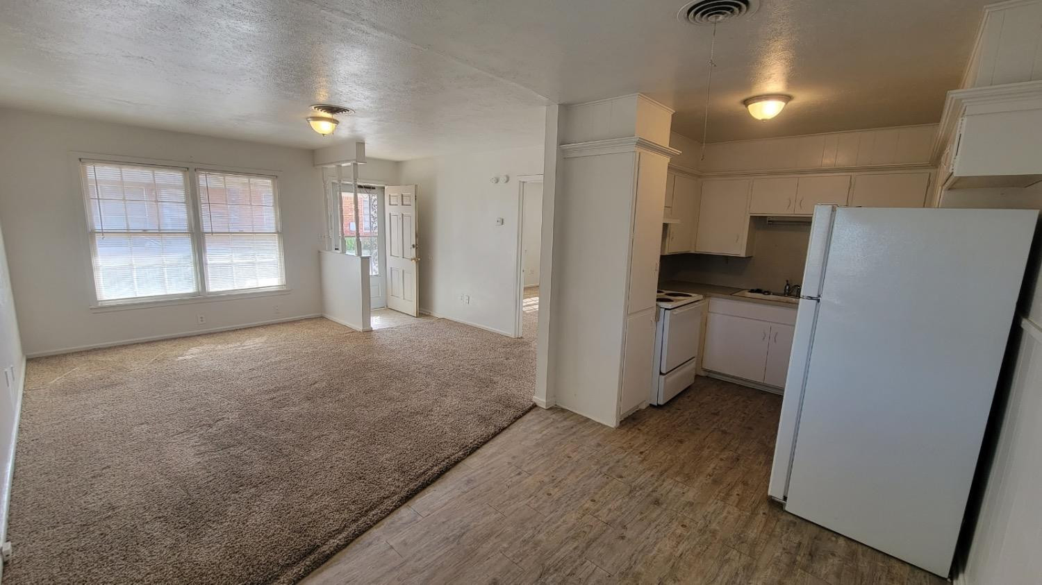 4205 50th Street, Unit A Lubbock, TX 79413 - Photo 7 of 10 a view of a kitchen with a refrigerator cabinets and a wooden floor