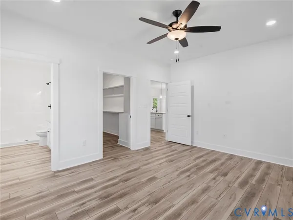 an empty room with wooden floor ceiling fan and window