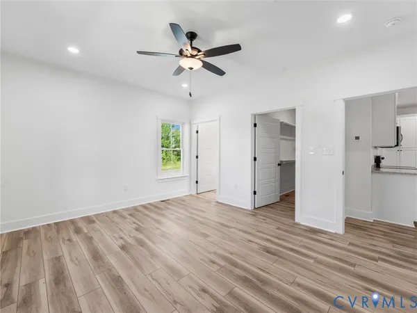 a view of empty room with wooden floor and ceiling fan