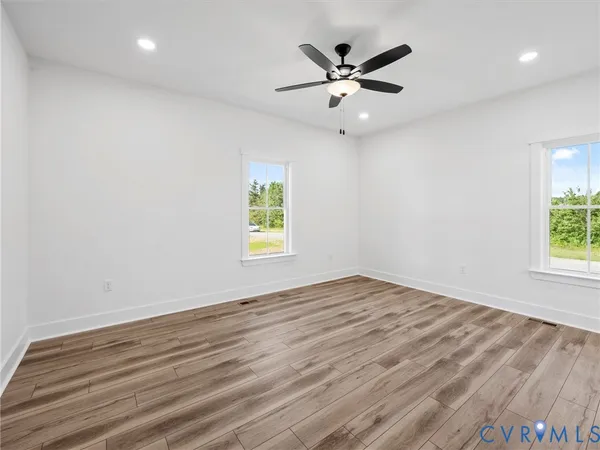 an empty room with wooden floor and windows