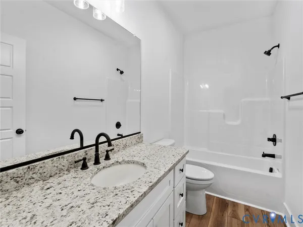 a bathroom with a granite countertop sink a toilet and shower