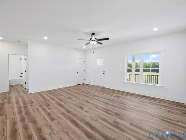a view of an empty room with a window and wooden floor
