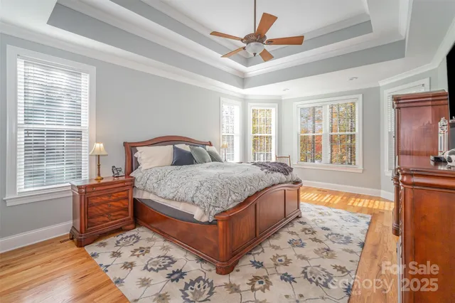 a bedroom with a large bed a chandelier and windows