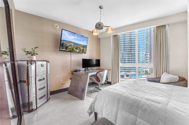 a bedroom with furniture a window and a flat screen tv