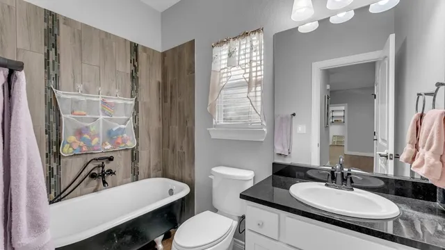 a bathroom with a granite countertop sink mirror vanity and a toilet