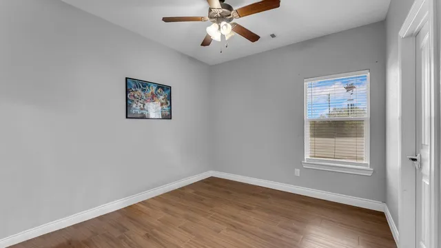 a view of an empty room with wooden floor and a window
