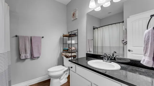 a bathroom with a granite countertop sink mirror and a toilet