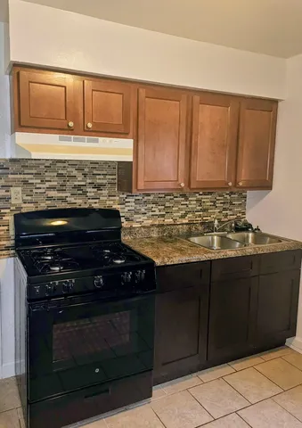 a kitchen with granite countertop a stove top oven microwave and cabinets