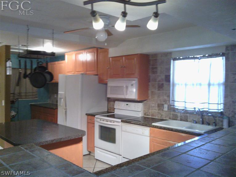 504 Penn Road West Lehigh Acres, FL 33936 - Photo 5 of 7 a kitchen with stainless steel appliances granite countertop a sink a stove and a refrigerator